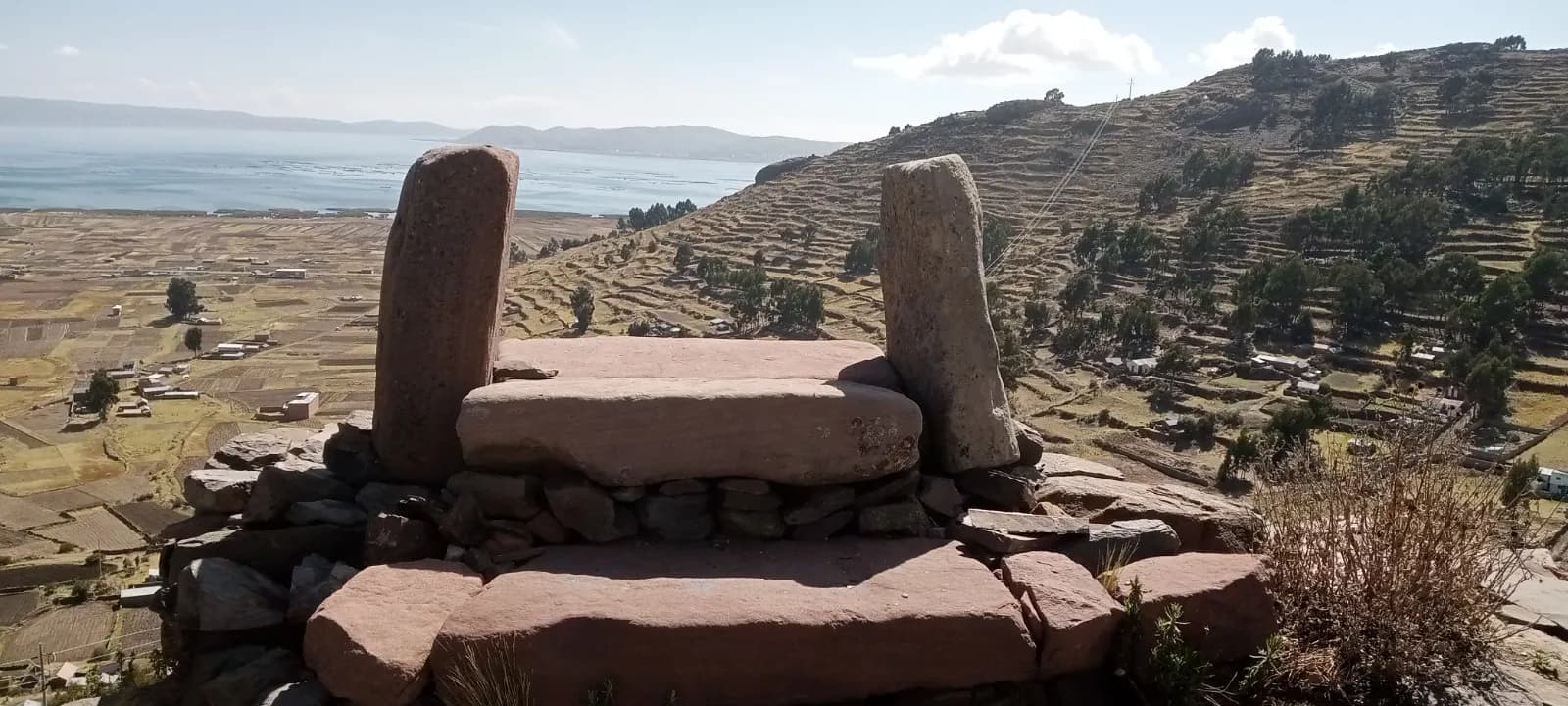 Stone altar above the farming terraces, Lake Titicaca on the horizon