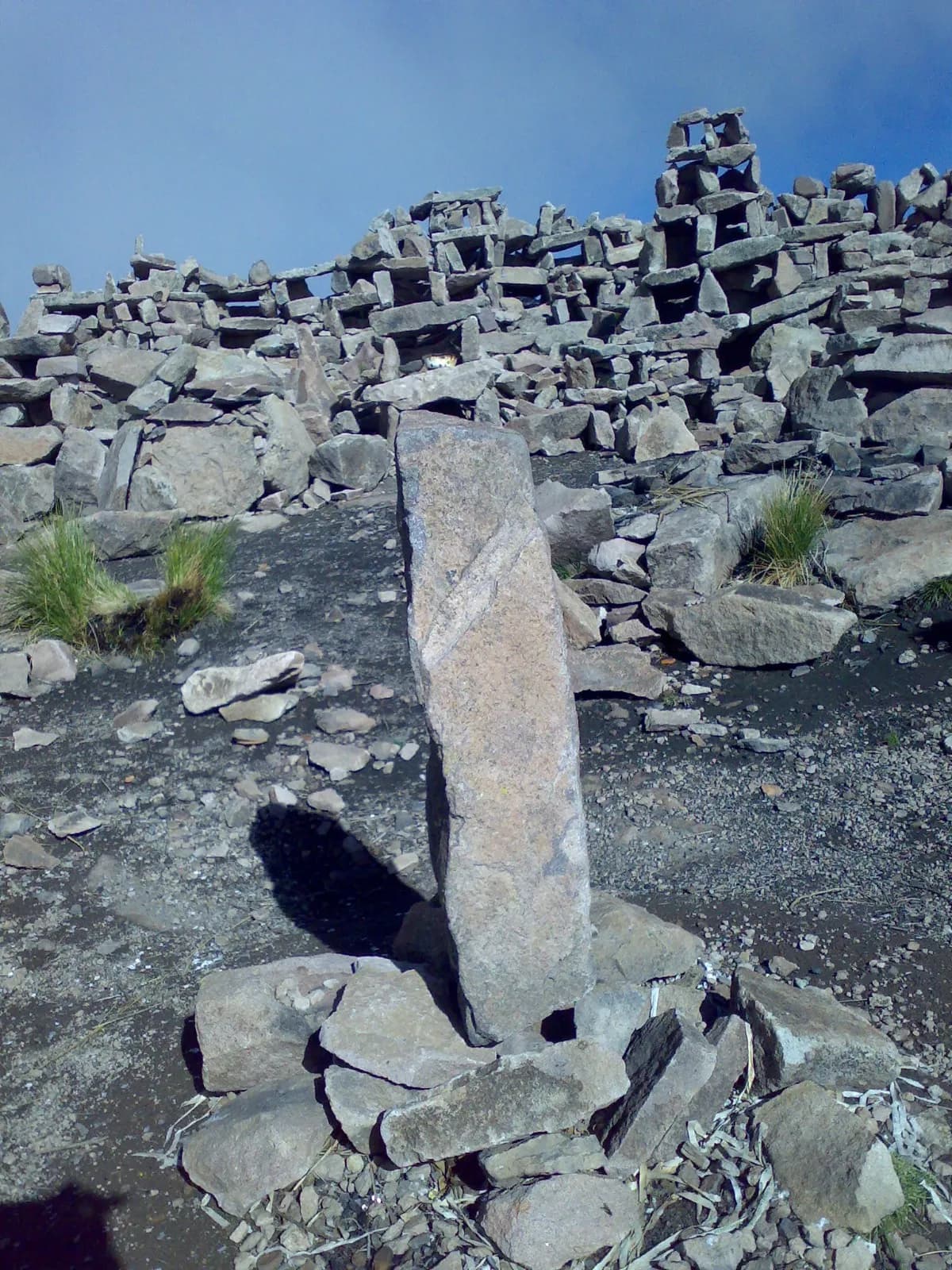 Apacheta: a monolith and towers of sacred stacked stones under the Andean sky