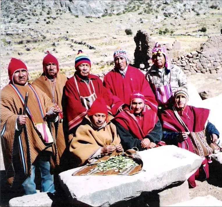 Circle of wise elders in red ponchos reading the coca leaves