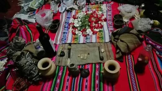 Andean offering mesa with white and red flowers on ceremonial textiles
