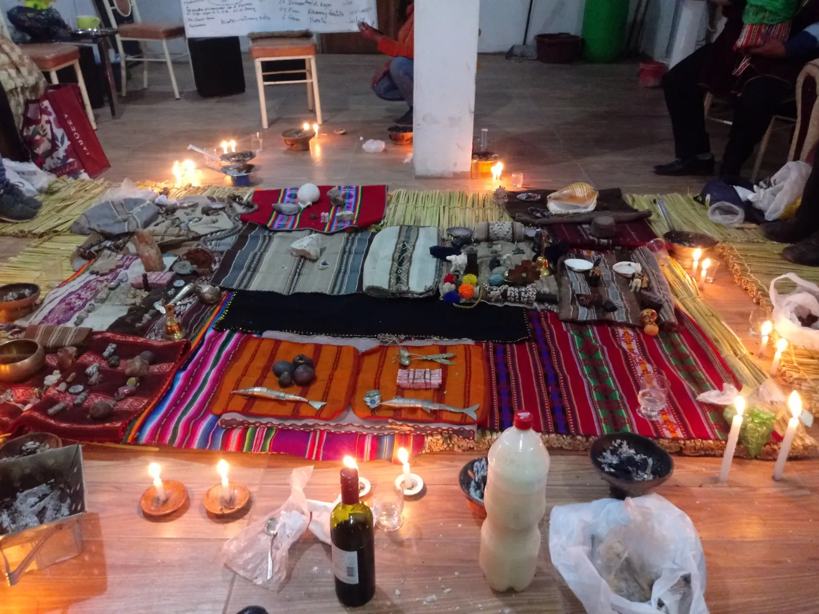 Andean ritual mesa with candles, textiles and offerings laid out on the floor