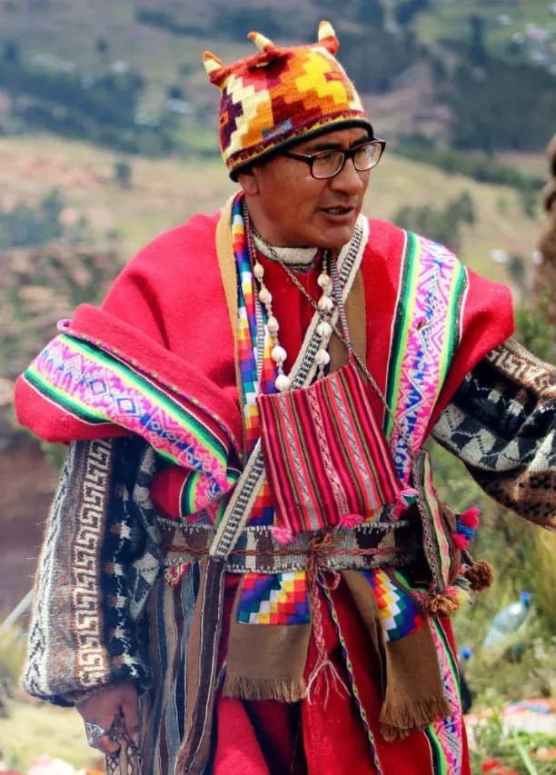 Portrait of an Andean guide wearing a woven chullo and red ceremonial poncho